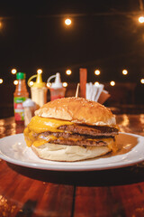 Triple cheeseburger on top of an outdoor restaurant table.