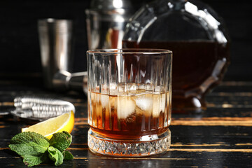 Glass of rum with lime and mint leaves on dark wooden background