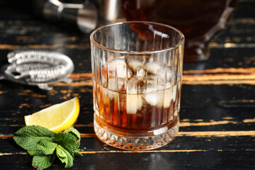 Glass of rum with lime and mint leaves on dark wooden background