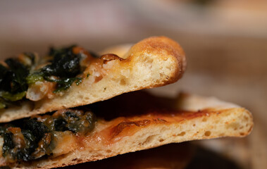 Two freshly sliced ​​pieces of pizza lie on top of each other. There are green vegetables on the pizza