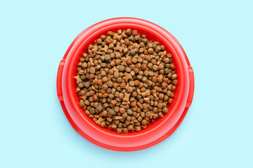 Red bowl of dry pet food on color background