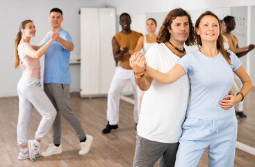 Positive people dancing together slow ballroom dances in pairs in choreography class