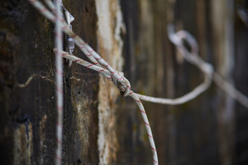 Close Up of climbing gear, Anchor, Rope, and Carabiner with cliff rock as a backdrop.