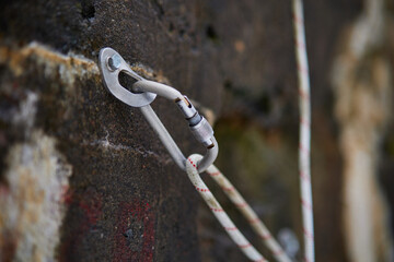 Close Up of climbing gear, Anchor, Rope, and Carabiner with cliff rock as a backdrop.