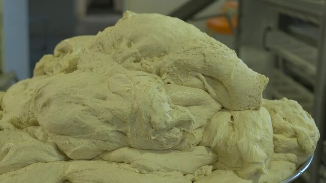 The process of kneading dough in a bakery. The baker collects the dough by hand.