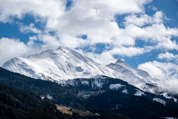 Mountain range of Austrian Alps, pointed rocks covered with snow above forest and meadow in winter.