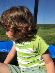 offended sad curly boy sitting on a trampoline