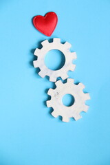 Gear wheels with heart symbol, blue background.