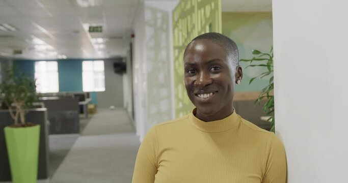 Portrait of smiling african american businesswoman with shaved head in office, slow motion