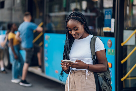 Portrait of an african american woman using smartphone on a bus stop