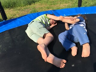 two brothers play and rest lie hugging on a trampoline