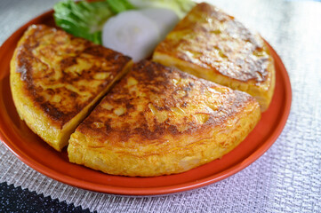Spanish vegetarian food, portion of homemade tasty potato omelette tortilla de patatas with onion served in morning sunlights