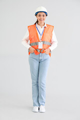 Female worker in vest on light background