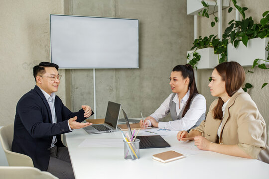 Diverse asian and caucasian people colleagues working together, discuss new project search solutions