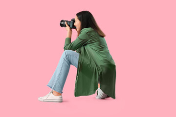 Obraz premium Female photographer with professional camera on pink background