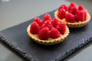 Artisanal baked small tart with cream and fresh ripe red raspberry