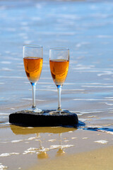 Two glasses of rose champagne or cava sparkling wine served on white sandy tropical beach and blue ocean water, romantic vacation, winter sun on Fuerteventura, Canary, Spain