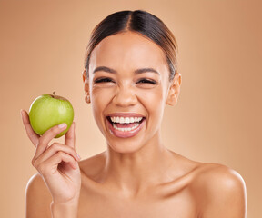 Portrait, beauty and woman with skincare, apple and smile with girl against brown studio background. Portrait, female and lady with fruit, diet and cosmetics with happiness, healthy lifestyle or joy