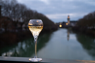 Glass of french sparkling white wine with bubbles champagne outdoor with view on green waters of...