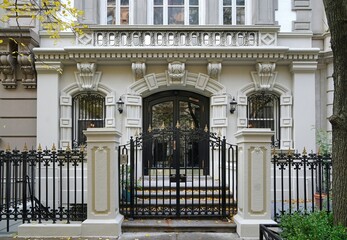 Front of elegant New York townhouse enclosed by fence and gate