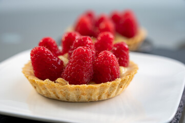 Artisanal baked small tart with cream and fresh ripe red raspberry