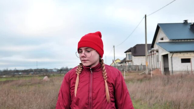 A sad teenage girl in red clothes is walking down the street.