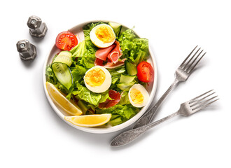 Plate of delicious salad with boiled eggs and jamon on white background
