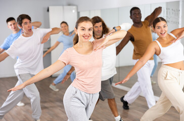 Group of energetic different people learning dance at dance class