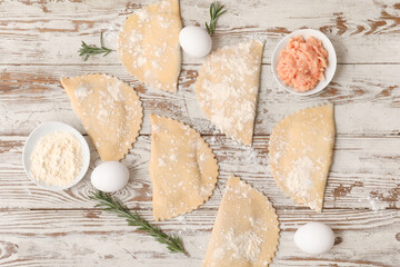Raw empanadas, forcemeat, flour, chicken eggs and rosemary on light wooden background