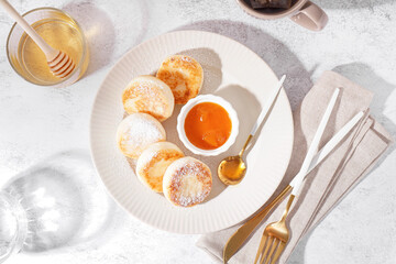 Plate with tasty cottage cheese pancakes, jam and honey on light background