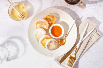 Plate with tasty cottage cheese pancakes, jam and honey on light background