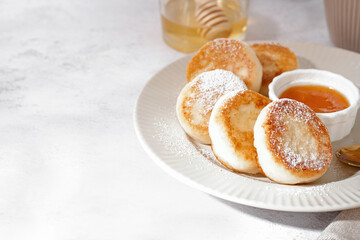 Plate with delicious cottage cheese pancakes and jam on light background