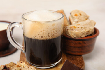 Delicious biscotti cookies and glass of coffee on white grunge background