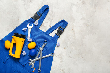 Plumber's uniform with tools, Easter eggs and flowers on grunge background