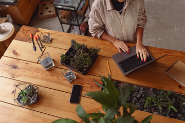 Top view of female florist working laptop in own floral studio, check customers order 