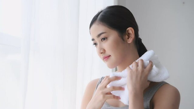 Holiday concept of 4k Resolution. Asian woman wiping sweat on her face with towel at home.
