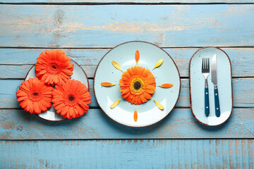 Table setting with beautiful gerbera flowers on blue wooden background