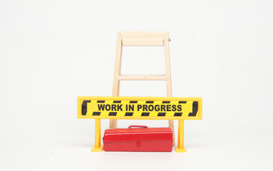 A picture of work in progress sign, tool box and ladder with hammer insight. Work in progress sign.