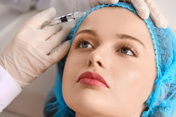 Young woman receiving filler injection  in beauty salon