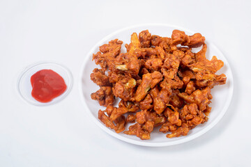 Crispy Fried Gobi Manchurian on white plate with ketchup on white background.