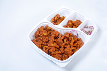 Fried Gobi Manchurian dry with sliced onions in plastic box on white background, popular Indian evening snack, side dish.