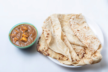 Popular Indian food on white background served with butter masala curry in a bowl with delicious butter naan on white plate, - obrazy, fototapety, plakaty