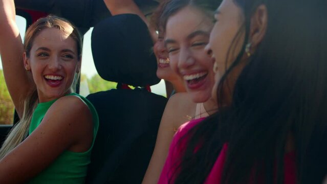 Vertical video of female friends in open top car posing for selfie laughing on road trip through countryside - shot in slow motion