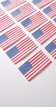 Vertical video of multiple national flags of usa lying with copy space on white background