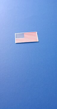 Vertical video of national flag of usa lying on blue background with copy space