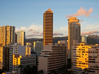 The high rise hotels of Honolulu's famous Waikiki neighborhood glow orange as the sun drops below the horizon