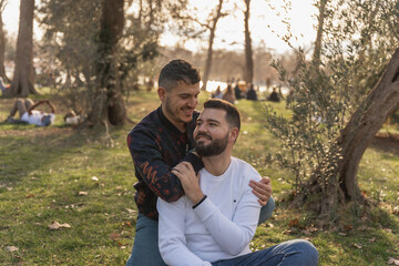 Naklejka na ściany i meble gay couple in the park, cuddling, loving and playful