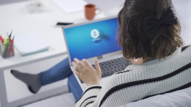 Home office worker woman enters password on her laptop.
The woman who enters the password on her laptop starts working on her opened laptop.
