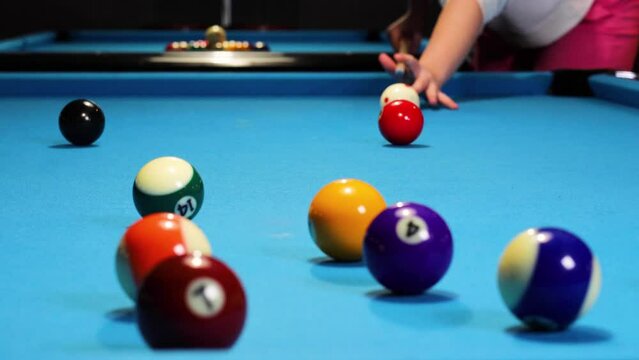Playing a game of pool billiards hitting balls with cue ball.
