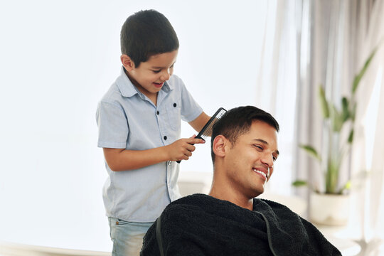 Father, family and kid comb hair in home for grooming, cleaning and styling. Smile, hairdresser and happy boy or child combing man and dad for new look or hairstyle while bonding and playing in house